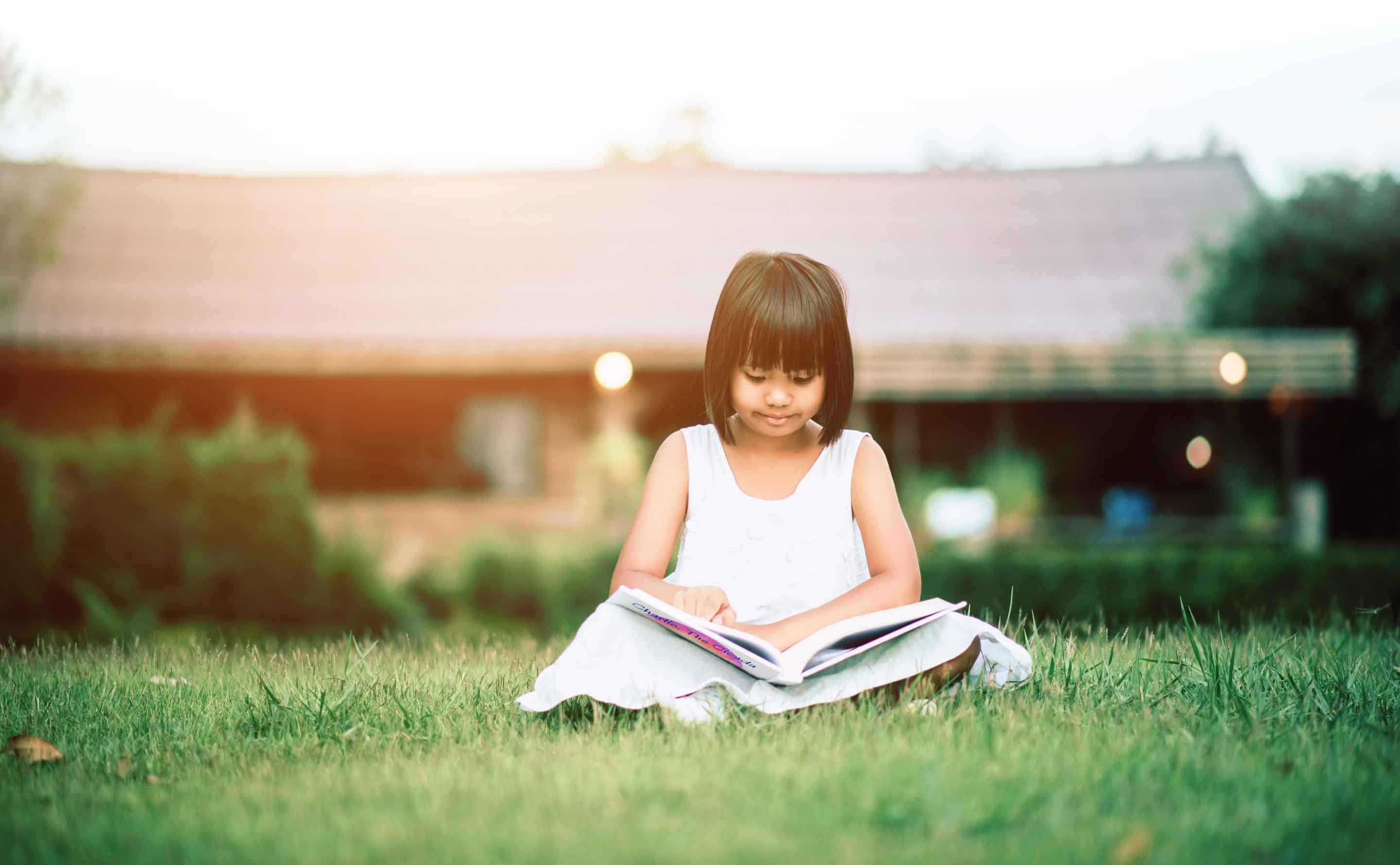 girl reading book in the grass